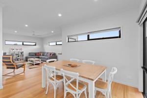 een witte woonkamer met een houten tafel en stoelen bij Mercer on Port in Portarlington