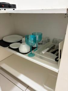 a refrigerator with two glasses and plates on a shelf at refugio pe na areia in Rio de Janeiro