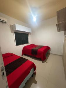 two beds in a room with red sheets and a window at Casa 3km da praia com piscina, 3 quartos, 2 km das praia do Aracagir in São Luís