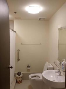 a white bathroom with a toilet and a sink at Luntian Luxury Condo in Tagaytay in Iruhin