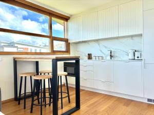 a kitchen with white cabinets and a counter with stools at Simple Comfort: Bridport Retreat in Bridport