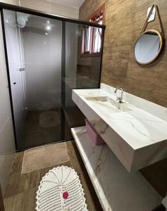 Un baño con lavabo y ducha con espejo. en Casa c Piscina Gigante, Lareira e Churrasqueira, en Campo Bom