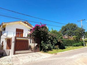 una casa blanca con una puerta y un arbusto en Casa c Piscina Gigante, Lareira e Churrasqueira, en Campo Bom