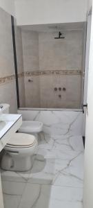Un baño blanco con inodoro y lavabo. en Departamento Vicco, en Pinamar