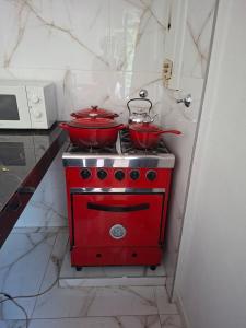 una estufa roja con dos ollas encima en Departamento Vicco, en Pinamar