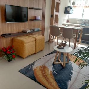 a living room with a television and a table and chairs at Comfortable departamento de 2 habitacones en la Victoria con garaje gratis in Ibarra