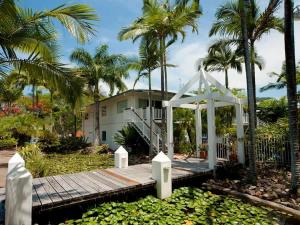 a wooden boardwalk leading to a house with palm trees at Mango Tides in Airlie Beach