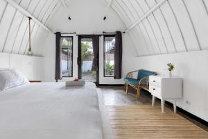 a white bedroom with a bed and a chair at TottyHouse Gili Trawangan in Gili Trawangan