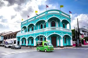 a green truck parked in front of a blue building at oo Mitr Inn Phuket Island - Phuket Old Town yes in Phuket
