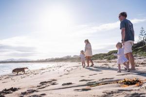 a family walking on the beach with a dog at Barlings Beach Holiday Park in Tomakin