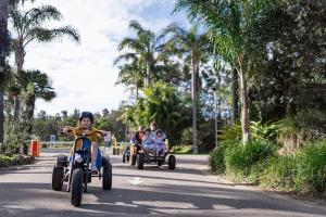 a group of people riding on tricycles down a road at Barlings Beach Holiday Park in Tomakin