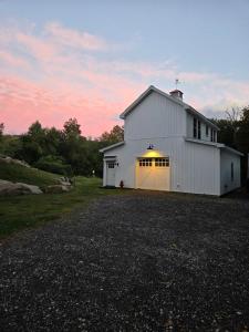 een witte schuur met een grote deur op een oprit bij Perch, for work or wandering the Litchfield Hills in Southbury