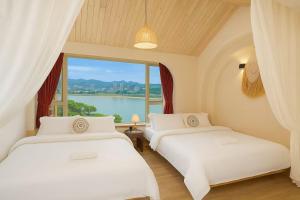 two beds in a room with a large window at Chongqing City Center River View B&B in Chongqing