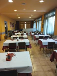 une salle à manger avec des tables et des chaises blanches dans l'établissement Fonda Ca La Maria, à Avinyó