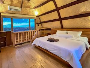 Makaha Bungalow في جيمباران: غرفة نوم بها سرير ونافذة كبيرة