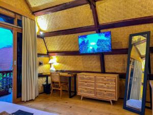 Makaha Bungalow في جيمباران: غرفة بها مكتب وتلفزيون على الحائط