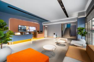 lobby biurowe z pomarańczowymi i białymi meblami w obiekcie Hanting Hotel Shenzhen Guanlan Foxconn w mieście Shenzhen