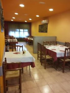 une salle à manger avec des tables, des chaises et un tissu de table blanc dans l'établissement Fonda Ca La Maria, à Avinyó