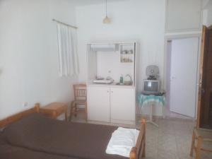 a bedroom with a bed and a kitchen with a microwave at Karagiozos Studios & Apartments in Skopelos Town
