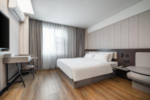 sypialnia z dużym białym łóżkiem i biurkiem w obiekcie Hanting Hotel Shenzhen Guanlan Foxconn w mieście Shenzhen +8 zdjęć