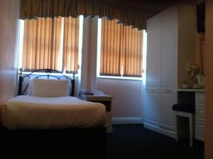 a bedroom with a bed and two windows and a bed sidx sidx sidx at Mermaid Suite Hotel in London