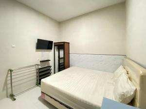 a small room with a bed and a flat screen tv at Modern Stay near Roxy Mall Jember RedPartner in Panti