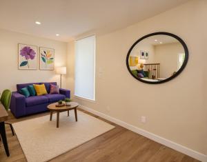 a living room with a purple couch and a round mirror at Boutique KTown Stays With Breathtaking Rooftop Views in Los Angeles