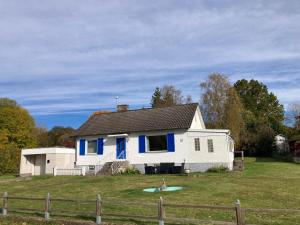 a white house with blue trim in a yard at Idyllic vacation home with lakeview in Grönskåra