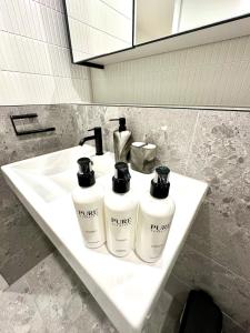 a bathroom sink with three bottles of toiletries on it at Manly Moon in Sydney +42 photos