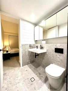 a bathroom with a toilet and a sink and a bed at Manly Moon in Sydney