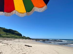 Iluka Sea Spray في إيلوكا: مظلة ملونة على شاطئ مع المحيط