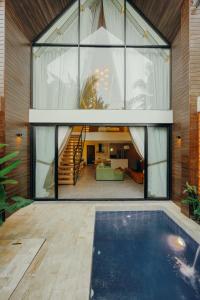 een glazen huis met een zwembad ervoor bij Moon Rock Villas by Ribas in Darmasaba