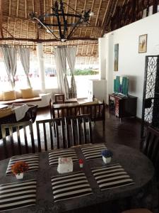 a dining room with a table and chairs and windows at Artistic Dreamsace 4Br Villa Near Diani Beach in Kwale