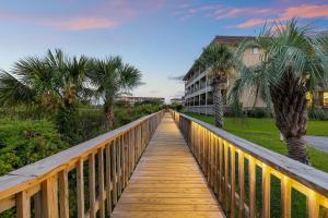 a wooden bridge with palm trees and a building at A145 HH Beach & Tennis Resort in Hilton Head Island