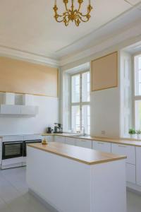 a large white kitchen with a chandelier at Manor With Soul Between Forest And Lake On Funen in Ullerslev