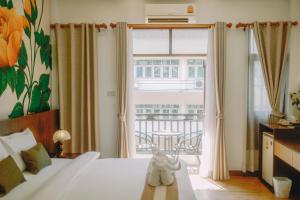 a bedroom with a bed and a window with a balcony at LA BURIE HOTEL Chiang Mai in Chiang Mai