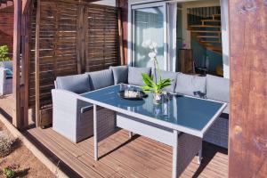 a glass table on a deck with a couch at Zironzine in Saint-Leu