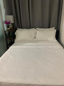 ein großes Bett mit weißen Laken und Kissen in der Unterkunft Robinson's Place Residences, in Manila + 2 Fotos