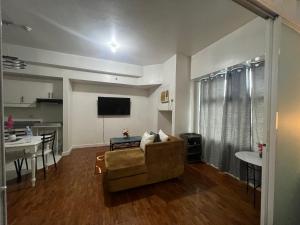 ein Wohnzimmer mit einer Couch, einem Fernseher und einem Tisch in der Unterkunft Robinson's Place Residences, in Manila