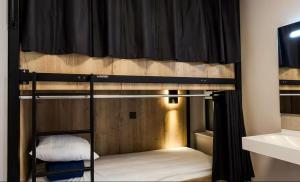 Auberge de Jeunesse Les Francas du Pas-de-Calais - ARRAS في Saint-Laurent-Blangy: سرير بطابقين في غرفة بها ستارة سوداء