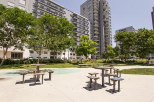 里斯本的住宿－Spacious Apartment in Lisbon，公园设有野餐桌、长凳和高楼