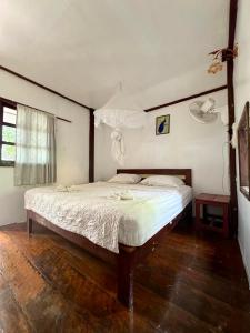 Un dormitorio con una cama grande con suelo de madera. en Tavendang Guesthouse, en Don Det