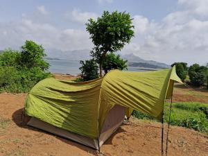 班达尔达拉Bhandardara I land Camping的一个盖着绿色顶棚的帐篷放在泥地上。 更多4张照片
