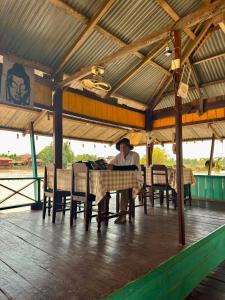 un hombre sentado en una mesa en un restaurante en Tavendang Guesthouse, en Don Det
