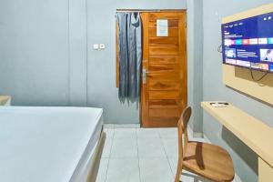 una habitación con un escritorio y una silla y un televisor en Nay Guesthouse near UMS Mitra RedDoorz, en Colomadu 9 fotos más