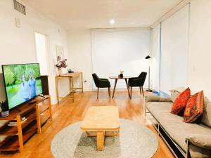 a living room with a couch and a tv and a table at Boutique KTown Stays With Breathtaking Rooftop Views in Los Angeles +74 photos