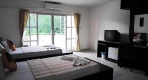 um quarto com 2 camas, uma televisão e uma janela em Warina Place Hotel em Ao Nang 