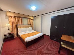 CabaguioD' Leonor Hotel的带床、梳妆台和书桌的卧室