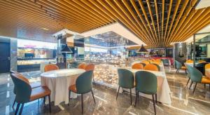 乌鲁木齐Urumqi Bayinhe Hotel的有桌椅和柜台的餐厅