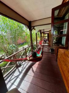 a person laying in a hammock on a porch at Tavendang Guesthouse in Don Det +8 photos